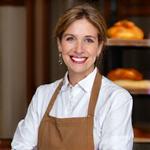 Portrait of Elara Vance, Head Baker, smiling warmly in a professional kitchen.