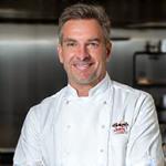 Portrait of Liam O'Connell, Executive Catering Chef, in a professional chef's uniform.