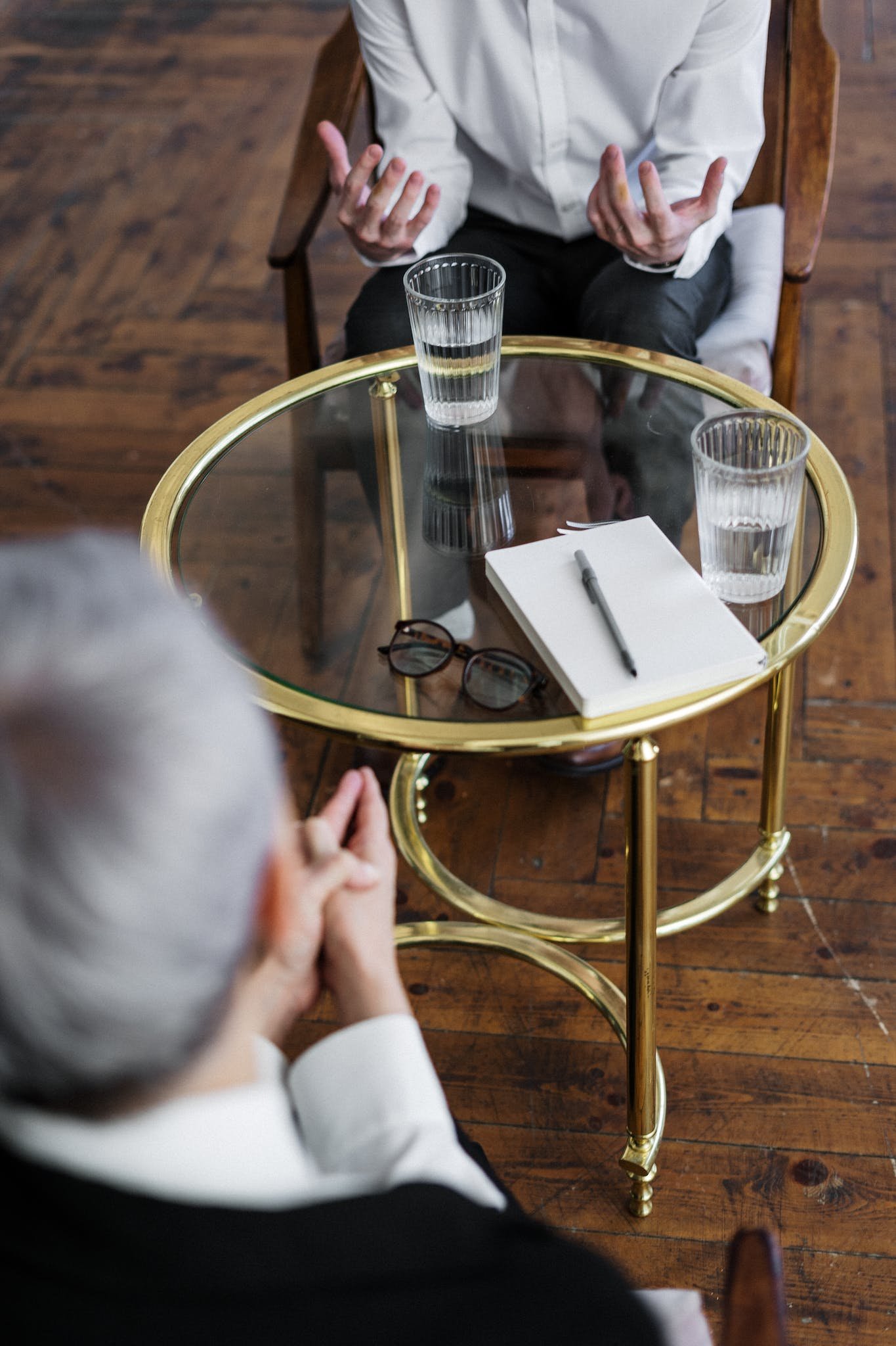 Woman in Black Long Sleeve Shirt Sitting on Brown Wooden Chair signifying coaching session